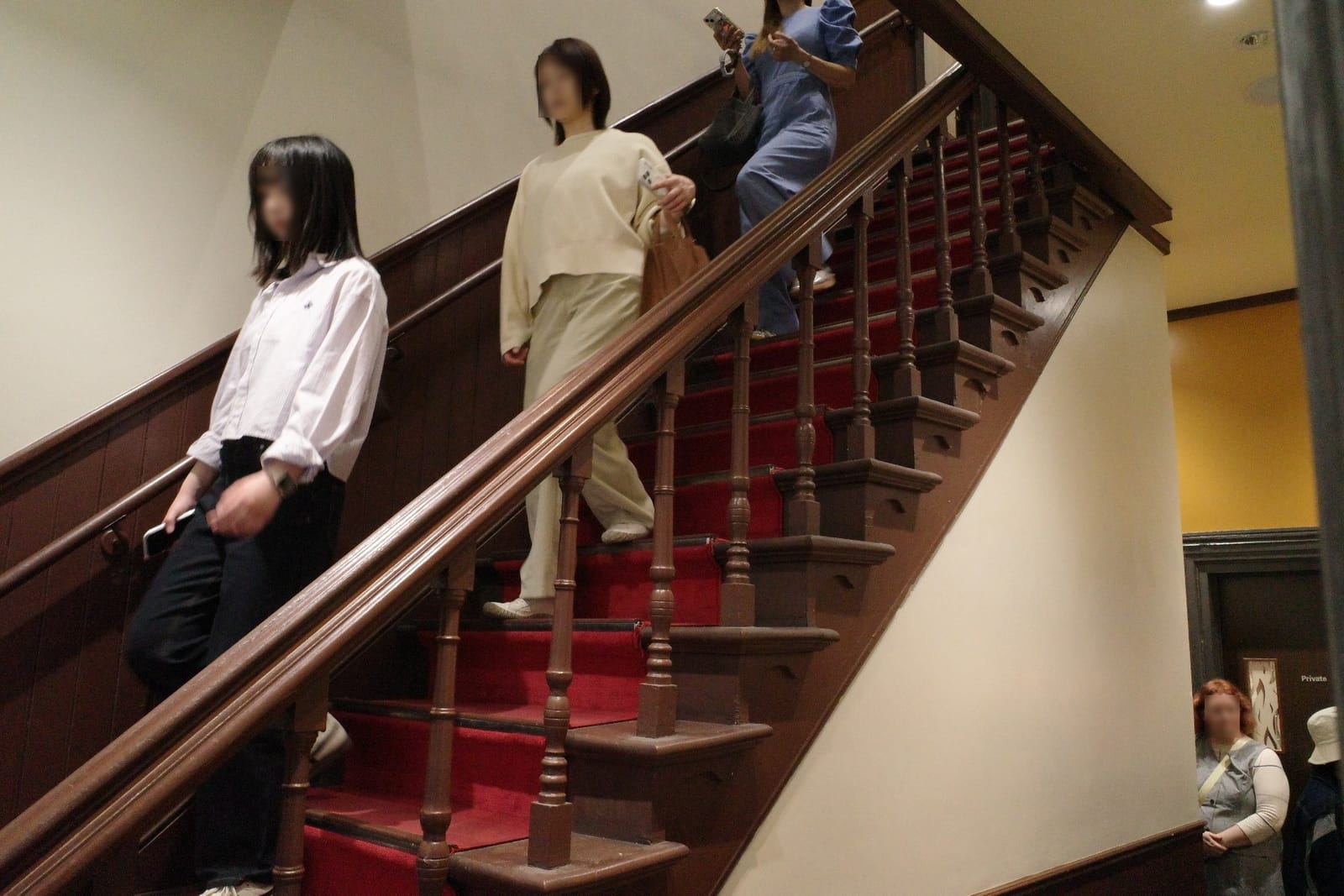 建物中央の木製階段。濃いブラウンの手すりと赤いカーペットが敷かれた、洋館らしい意匠
