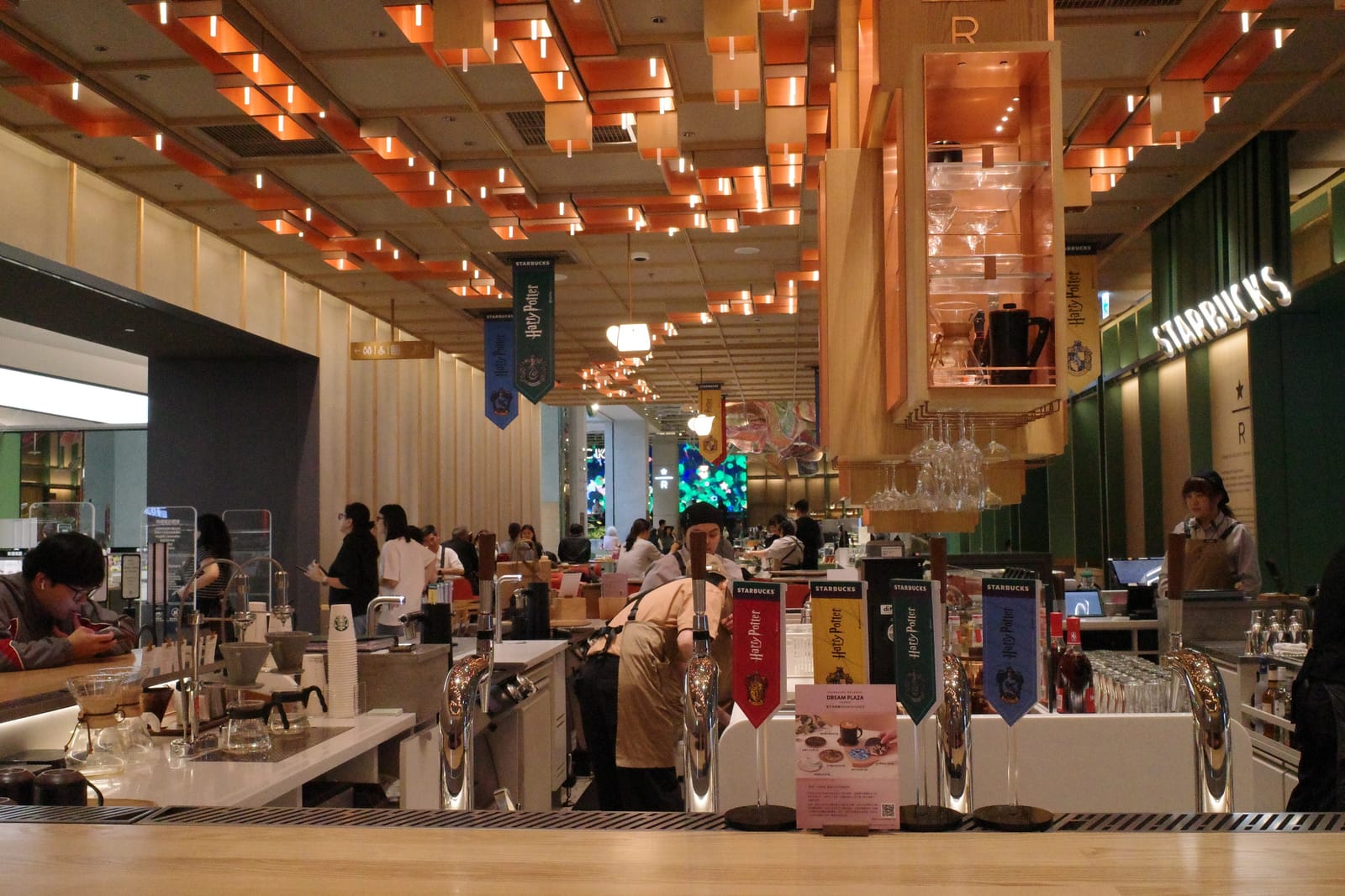 店の中央にある Reserve のサーブカウンター。サイフォン式抽出やエスプレッソマシンが並び、頭上にはオレンジ色のリボン状装飾が連なる